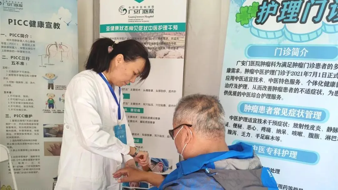 Guang’anmen Hospital oncology nurse demonstrating gua sha on a participant at an offsite TCM health event; this does not depict the international clinic