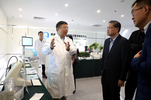 Hospital staff describing clinical equipment during Beijing health authority visit